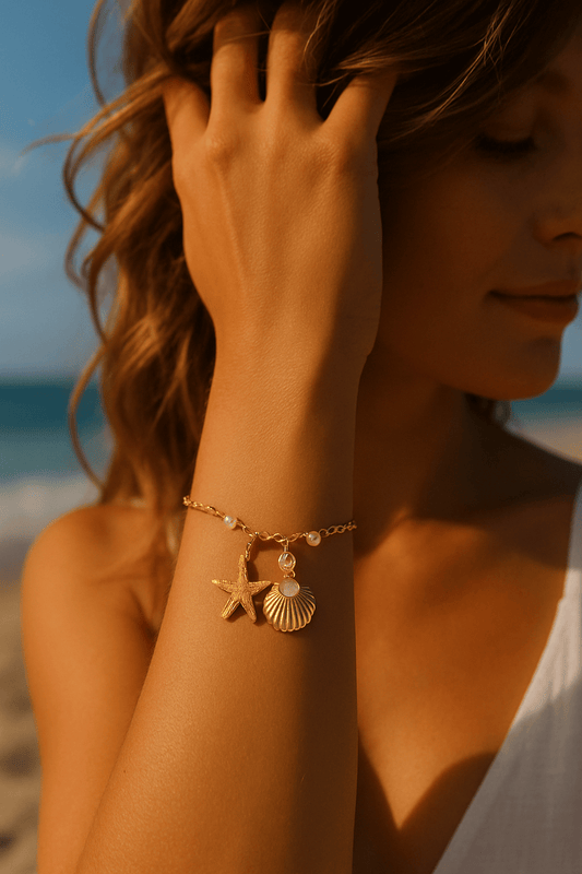 Model wearing gold bracelet with starfish and shell charms, accented with pearls – ORL’A Jewelry Store summer accessory